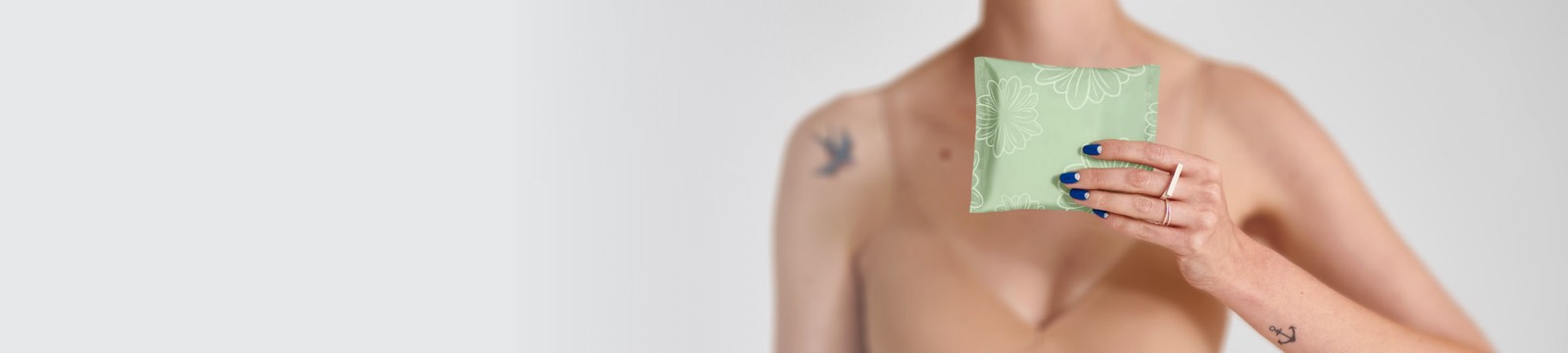 Žena v podprsenke, ktorá pred sebou drží jednu vložku TENA